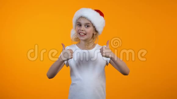 戴着圣诞帽的微笑少女竖起大拇指准备圣诞假期视频的预览图