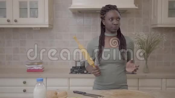 美国非洲美女拿着擀面杖站着想着在现代的背景下准备馅饼视频的预览图