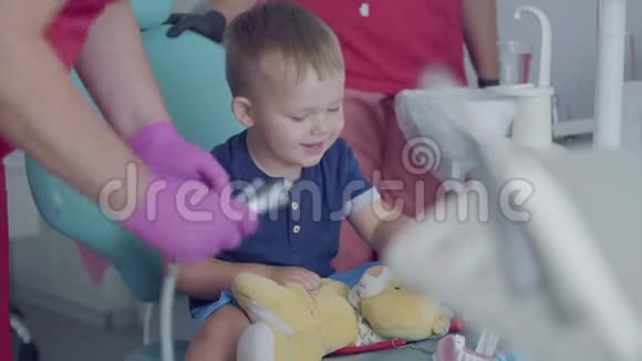 可爱的小男孩坐在牙医办公室的椅子上玩医疗工具免费儿童探访视频的预览图