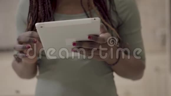 近距离观看非洲裔美国妇女手拿白色平板电脑上网与朋友聊天视频的预览图