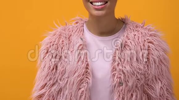 现代女性穿着粉色毛皮外套双手交叉着黄色背景视频的预览图