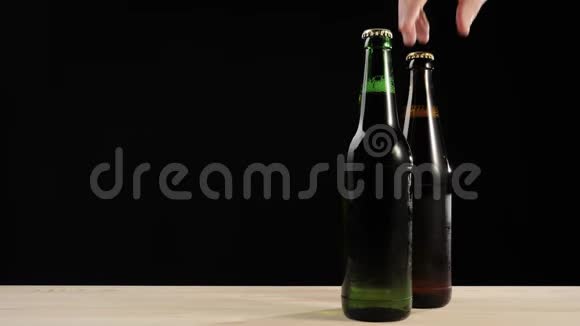 新鲜啤酒手拿着一个棕色的瓶子里面有美味的手工啤酒靠近绿色的瓶子还有木桌上的啤酒视频的预览图