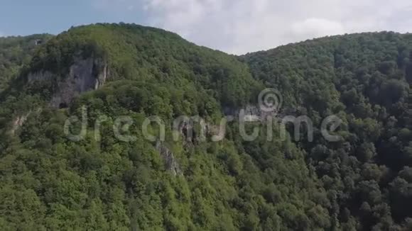 瀑布在布满森林的岩石山坡上的空中景色视频的预览图