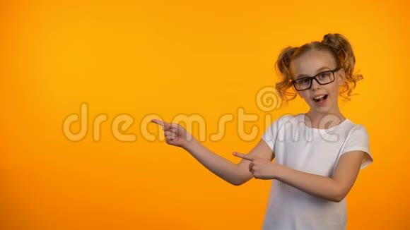 戴眼镜的漂亮女孩指着橙色背景教育机会视频的预览图