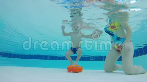 小男孩在妈妈的帮助下把玩具从水下举视频的预览图