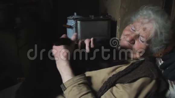 一位白发苍苍的老妇人抱着她的黑猫和她玩微笑着住在一个废弃的村庄里视频的预览图