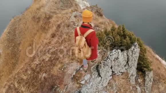 一位戴着黄色帽子的女摄影师带着一个背包沿着一条山路到一个视频的预览图