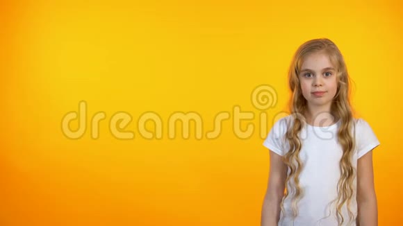 满意的可爱女孩指向橙色背景广告模板视频的预览图