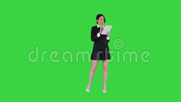 可爱的女人穿着裙子跳舞在绿色屏幕上使用数字平板电脑色度键视频的预览图