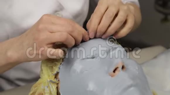 美容师在水疗沙龙为女人的脸摘下泥面膜面部年轻化程序水疗视频的预览图