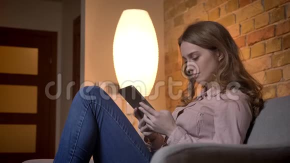 年轻少女使用平板电脑打字的肖像在舒适的家庭氛围中积极微笑视频的预览图