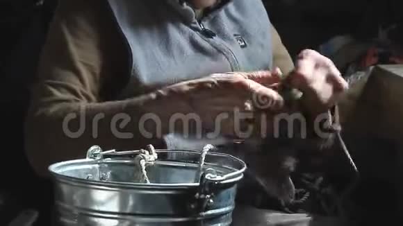 一个老妇人双手酸痛在绳子上打结把水桶放在井里生活在一个废弃的村庄里视频的预览图
