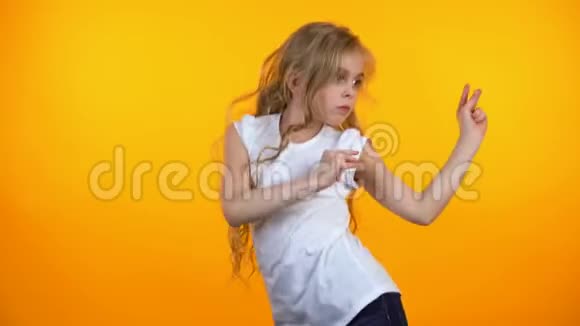 有趣的十几岁女孩跳舞移动到音乐孤立的橙色背景视频的预览图