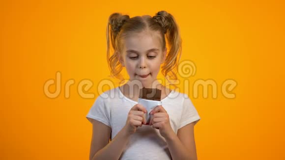 快乐的微笑少女吃着美味的巧克力享受着甜蜜的味道视频的预览图