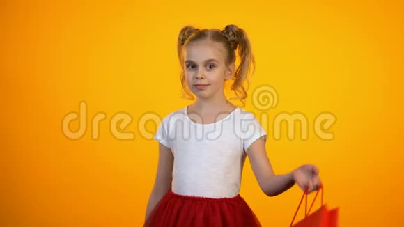 美丽的女孩带着红色购物袋摆姿势对着相机眨眼购物视频的预览图