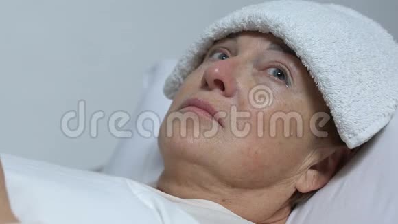 护士用毛巾喂哭泣的老妇人额头病后残疾视频的预览图
