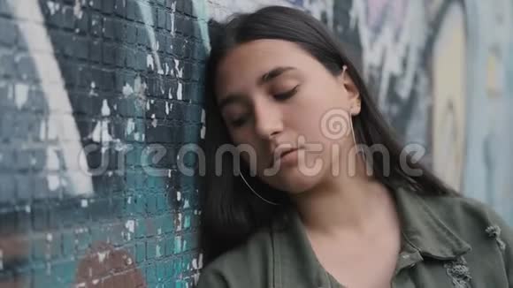 一个年轻的黑发少女在墙边涂鸦的肖像视频的预览图