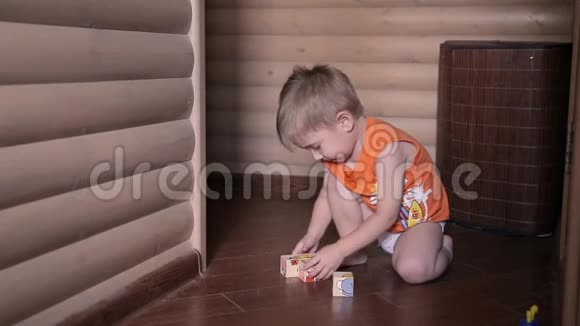 快乐的孩子玩立方体他穿着橙色T恤房间里有木墙视频的预览图