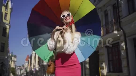 正色美女看着镜头拿着五彩伞走在大街上时尚迷人视频的预览图