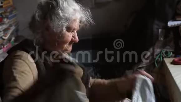 一个白发苍苍的老妇人整理旧东西在她的老房子里打扫床独自生活视频的预览图
