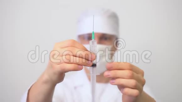 男性医务人员穿白色衣服和口罩用手拿注射器视频的预览图