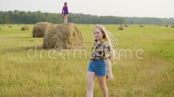 穿着格子衬衫和帽子的牛仔在农村的收割场上行走干草堆景观上的乡村女孩视频的预览图