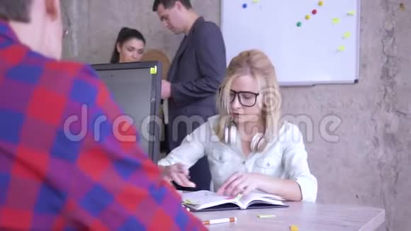 戴眼镜的女商人坐在办公桌前在笔记本上写笔记在电脑上贴上彩色贴纸视频的预览图