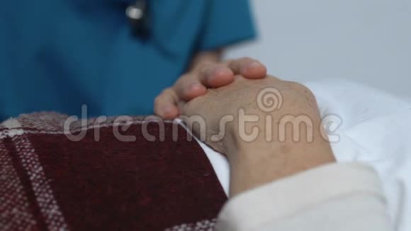 护士将女性病人的手躺在床上患有不治之症视频的预览图