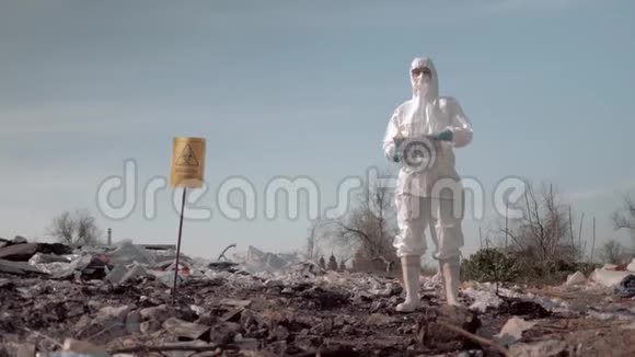 穿防护服戴防护面具的妇女在附近的垃圾场张贴防止污染标语视频的预览图