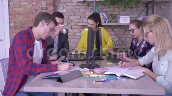 活跃的年轻上班族在笔记本上写着有创意的笔记在现代办公室的桌子上贴着彩色贴纸视频的预览图