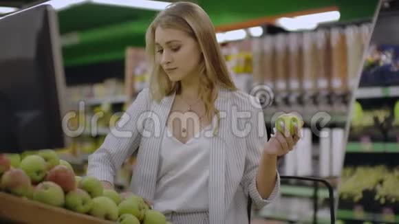 有魅力的年轻女性在水果蔬菜超市市场选择苹果视频的预览图