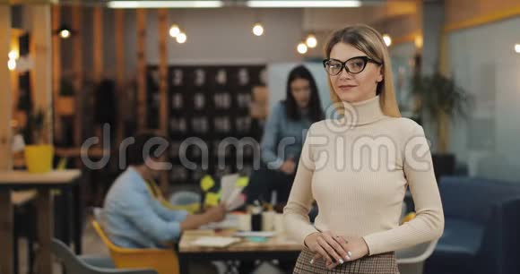 年轻成功女商人的肖像戴着时尚眼镜看着办公室工作空间里的相机工作视频的预览图