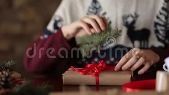 近景男士他的手在壁炉旁的圣诞礼物上系蝴蝶结包装盒子用冷杉装饰视频的预览图