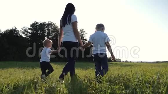 一位年轻的母亲和她的孩子在绿草上散步快乐的家庭在新鲜的地方度过他们的假期视频的预览图