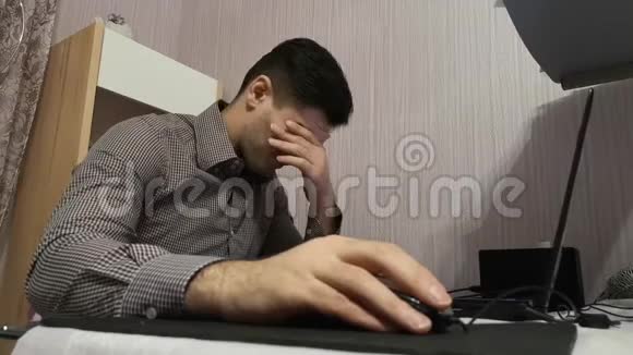 年轻人用笔记本电脑擦拭眼睛以免疲劳视频的预览图