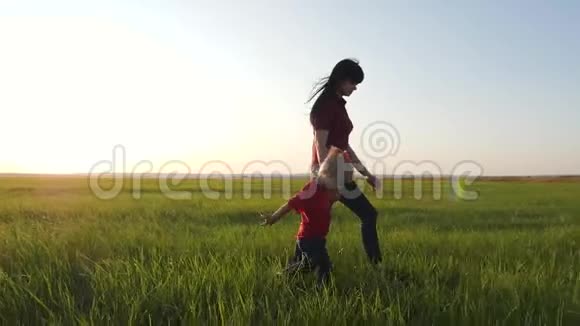 一位年轻的母亲和她的金发女儿在新鲜空气中散步幸福的一家人走在绿草上视频的预览图