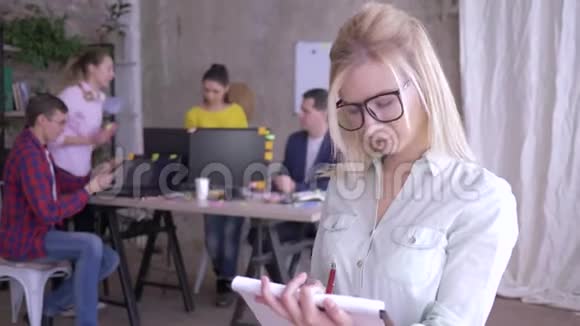 戴眼镜的快乐女办公室职员在纸上做笔记然后对着镜头微笑的画像视频的预览图