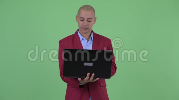 快乐的秃头多民族商人使用笔记本电脑思考视频的预览图