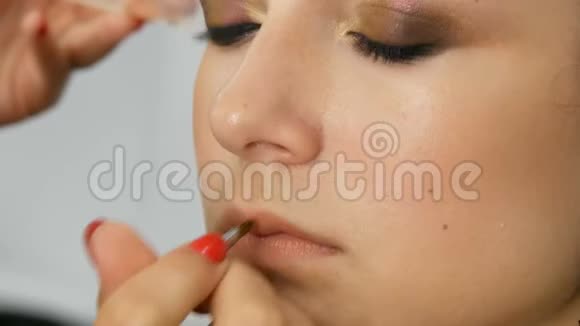 年轻可爱的红发少女在美容院用一支特制的刷子化妆嘴唇视频的预览图