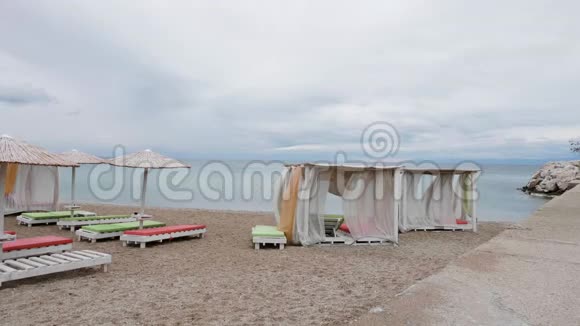 空的日光浴床矗立在碧海边的沙滩上视频的预览图