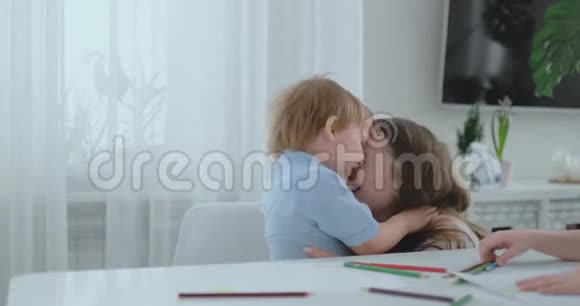 妈妈拥抱并赞美她的儿子是一幅很好的礼物画家庭中的爱和温暖的关系视频的预览图
