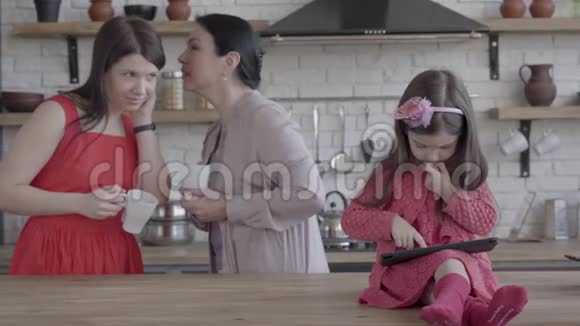 祖母母亲和小达格特在厨房里那个坐在桌子上玩平板电脑的女孩视频的预览图