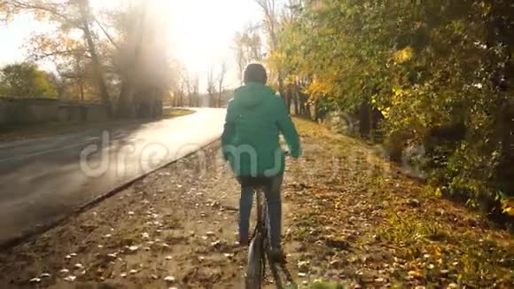 体育自行车骑在秋天的公园里背景是黄色的树体育生活方式的概念穿绿色衣服的年轻女孩视频的预览图