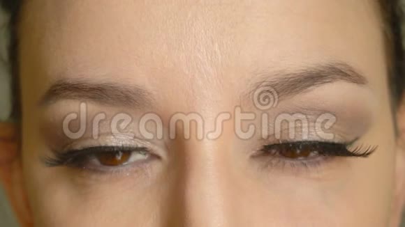 长着假睫毛的女性脸打开棕色的眼睛看着相机特写美女模特视频的预览图
