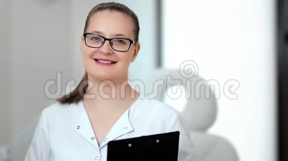 中等特写照片微笑的年轻女医生戴着眼镜摆姿势看着镜头视频的预览图