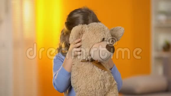 玩具可爱的女孩躲在毛绒玩具后面对着镜头微笑学龄前儿童视频的预览图