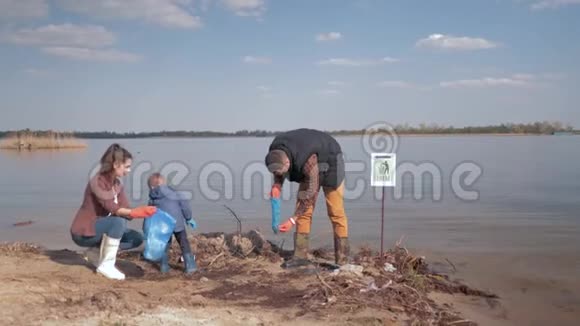 环保解决方案儿童男孩帮助母亲和父亲的志愿者清理肮脏的河岸塑料视频的预览图