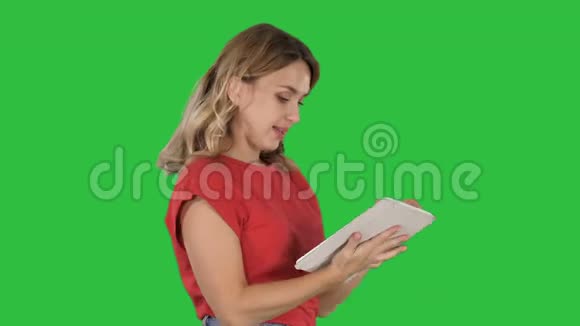 女士穿红色t恤使用平板电脑在绿色屏幕铬键视频的预览图