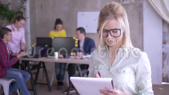 快乐的女办公室职员戴着眼镜在纸上做笔记然后对着镜头微笑视频的预览图