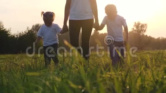 一位年轻的母亲和她的孩子在绿草上散步快乐的家庭在新鲜的地方度过他们的假期视频的预览图